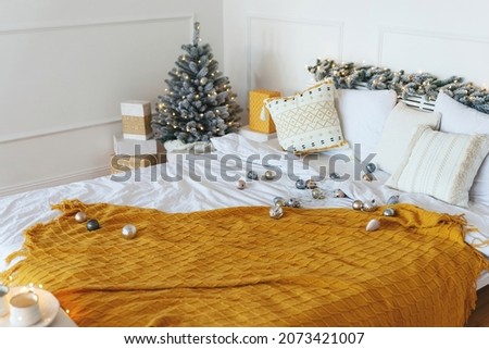 Pre-holiday Christmas bustle. Christmas decorations scattered on the bed decorated with a garland. In the far corner there is a small Christmas tree and gifts. New Year's Eve mood, winter holidays. 