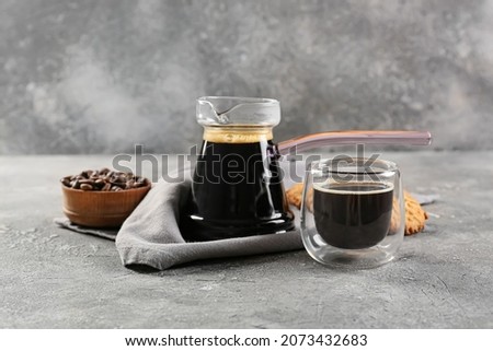 Cezve and cup with delicious turkish coffee and cookies on grey background