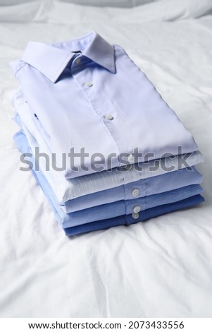 Stack of stylish male shirts on fabric background