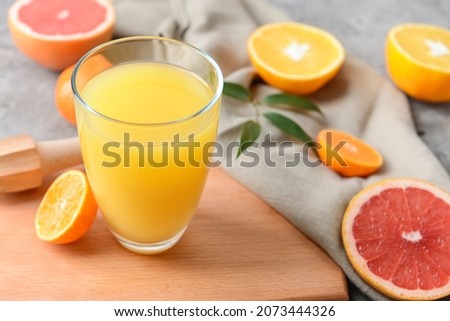 Glass with tasty citrus juice on grey background