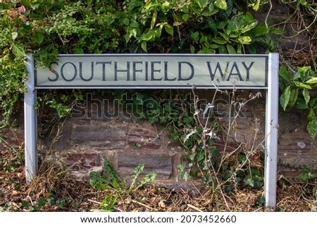 Southfield Way street name sign on two posts with an old stone wall and ivy in the background