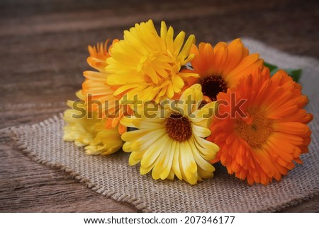 Bouquet of calendulas on canvas on old wooden background