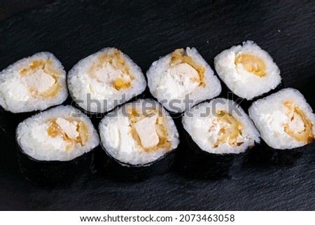 Macro shot of hosomaki sushi with soy sauce on natural black slate plate background with selective focus. Sushi with salmon and avocado