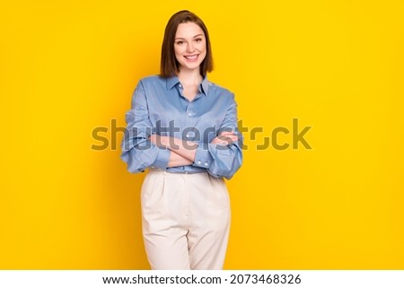 Photo of adorable cute young woman wear blue shirt smiling arms crossed empty space isolated yellow color background