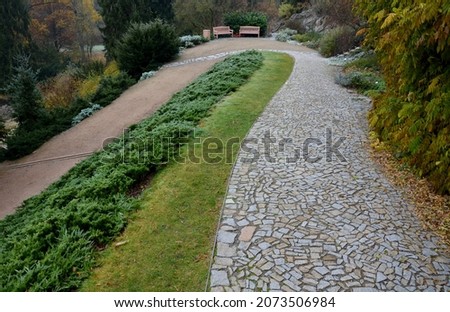 stabilization of the slope with the help of wooden slats, which with the help of wires hold soil on the slope. granite park paths and perennial flower beds with benches. historic garden above lake  Royalty-Free Stock Photo #2073506984