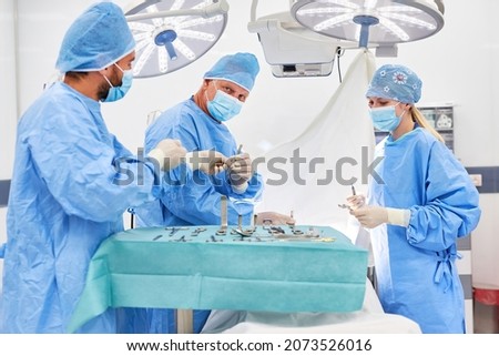 Resident physician and operating room nurse assist senior physician in the emergency operation in surgery Royalty-Free Stock Photo #2073526016