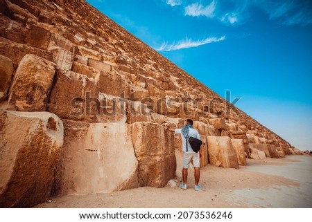 A man tourist stands near the huge blocks of the Giza pyramid near Cairo.
