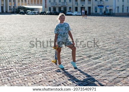Teenage girl with a skateboard in the city center on a warm summer evening.