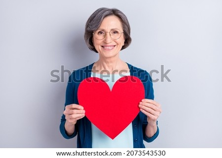 Photo portrait of happy business woman smiling keeping red heart shaped postcard isolated on grey color background