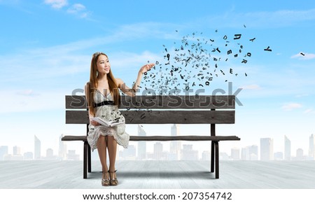 Young pretty asian woman sitting on bench and reading book