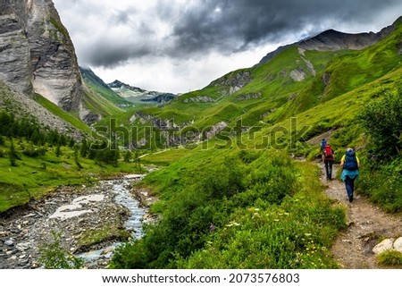 People Hike Through Alpine Valley With River To Mountain Peak Grossglockner in Tirol in Austria