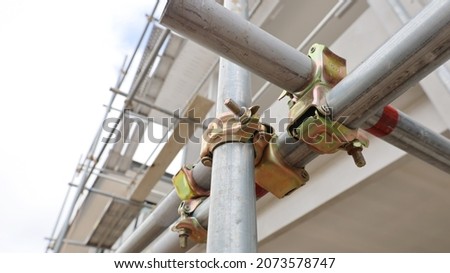 Metal scaffolding pipe clamp. Steel scaffolding and mounting parts for strength in construction sites or supports in view below. Close-up and select focus Royalty-Free Stock Photo #2073578747
