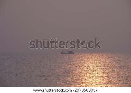 Villagers' fishing boats fish in the sea with the orange sunlight reflecting on the water in the evening. It's a beautiful picture.