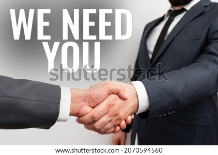 Sign displaying We Need You. Word Written on asking someone to work together for certain job or target Two Professional Well-Dressed Corporate Businessmen Handshake Indoors Royalty-Free Stock Photo #2073594560