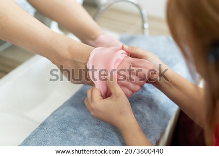Beautiful Asian young woman having a paraffin foots and hands spa at beauty - spa shop. Foot and hand paraffin treatment. Royalty-Free Stock Photo #2073600440