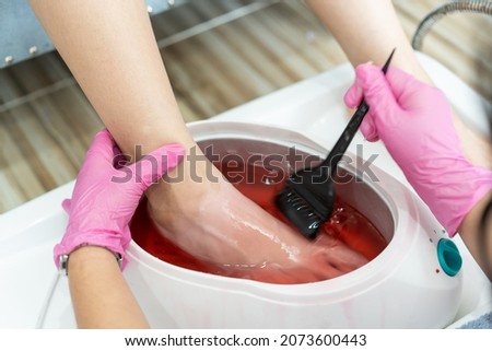 Beautiful Asian young woman having a paraffin foots and hands spa at beauty - spa shop. Foot and hand paraffin treatment. Royalty-Free Stock Photo #2073600443