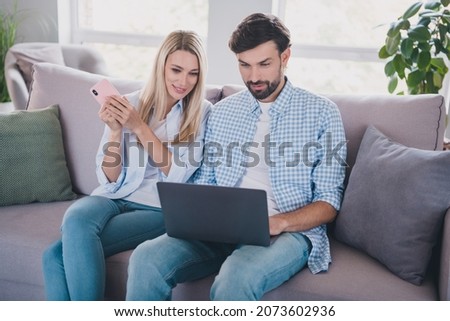 Photo of positive couple sit couch share family account app wear casual outfit in comfortable home indoors