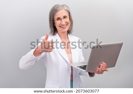Photo of hr white hairdo aged lady hold laptop show thumb up wear spectacles jacket isolated on grey color background