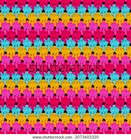 Seamless knitted texture. The pattern is crocheted from bright multi-colored acrylic yarn. African motives. Royalty-Free Stock Photo #2073603320
