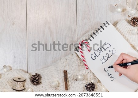 2022 GOALS list. Top view hand holding pen writing Goals 2022 in notebook over white wood background Royalty-Free Stock Photo #2073648551