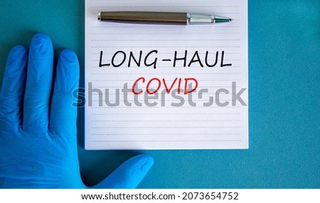 COVID-19 long-haul covid symptoms symbol. White card with words long-haul covid. Doctor hand, pen, beautiful blue background, copy space. Medical, COVID-19 long-haul covid symptoms concept.