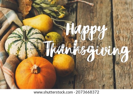Happy thanksgiving text on pumpkins, autumn leaves, pears, cozy blanket on rustic old wood. Seasonal greeting card, handwritten sign. Give thanks