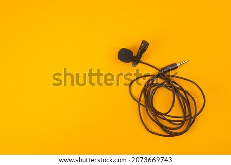 Lavalier microphone on a yellow background. Copy space.