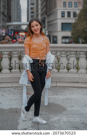 A vertical of a cheerful stylish young beautiful Hispanic female posing on the street