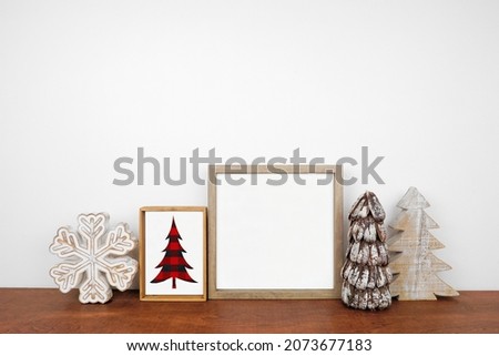 Christmas mock up with wood frame, rustic decor and buffalo plaid sign. Square frame on a wood shelf against a white wall. Copy space. Modern farmhouse concept.