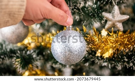 Merry christmas and happy holidays, hand of a man is decorating the spruce tree indoors home at winter. Xmas stars hanging of fir branches for decoration banner, New Year concept.
