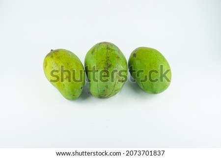 Three mangoes with green skin on white background