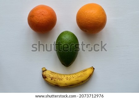 Funny face made of oranges, avocado and banana on white table. Top view Royalty-Free Stock Photo #2073712976