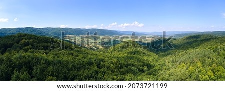 Aerial view of mountain hills covered with dense green lush woods on bright summer day. Royalty-Free Stock Photo #2073721199