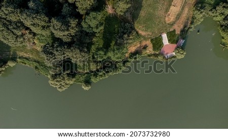 Aerial top view shot of strange Green water river swamp with lot of green trees and cozy countryside dirt road made at summer in Ukraine