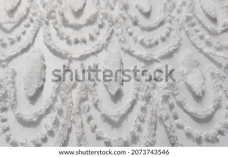 Light beige translucent fabric with a stencil plant print and lace effect, on a white background (macro, top view, texture).