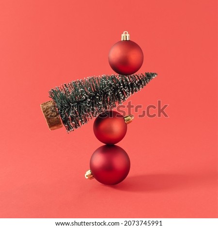 Christmas tree and red Christmas baubles against red background. Creative holiday composition. Minimal New Year concept.