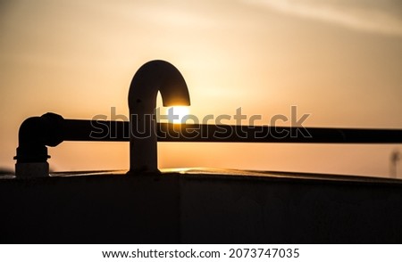 The bright sun behind the railings on the roof of a building
