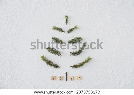 Homemade Christmas tree with white background and conifer brunches in copyspace flat lay do it yourself minimalism on snow with 2022 new year cubes