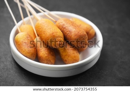 Corn dog cooked with sausage and wheat dough with the addition of corn flour, on a dark background Royalty-Free Stock Photo #2073754355