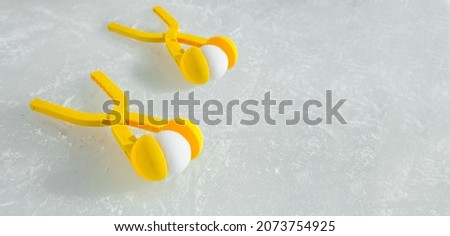 Two yellow toy snowball Making  tools are lying on an ice rink. Winter children's outdoor outdoor games. A snowball fight. Banner with copy space