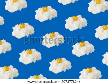 Golden gift box on cotton cloud against blue background. Creative Christmas holiday pattern.