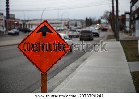 A orange signage with "construction" text along the road
