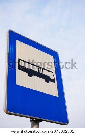 A vertical low angle of a blue bus stop sign
