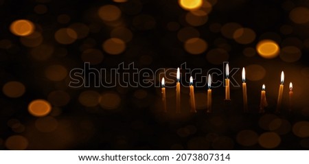 Nine Chanukah candles with dark bokeh lights background web banner