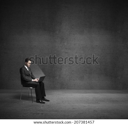 businessman sitting in dark room with laptop
