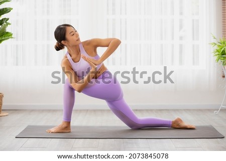 Individual hatha yoga instructor training Parivrtta Anjaneyasana crescent lunge on knee prayer hands modern by Asian lady trainer. Royalty-Free Stock Photo #2073845078