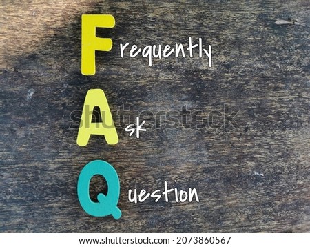 Word FAQ made of colourful wooden alphabet against wooden background.