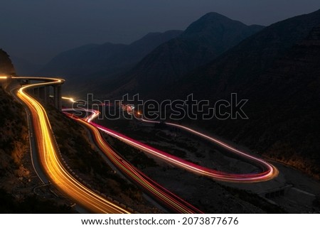 landscape with beautiful light trails on the zigzag road in the mountains valley 