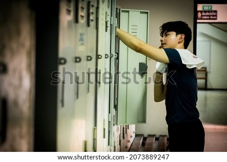 Side view a young Asian athletic man with a towel in the locker room after  exercising  with copy space for text or design. Concepts of health, sports and wellness.