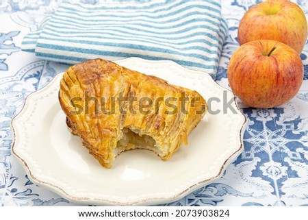 piece of apple pie and two fresh apples on table
